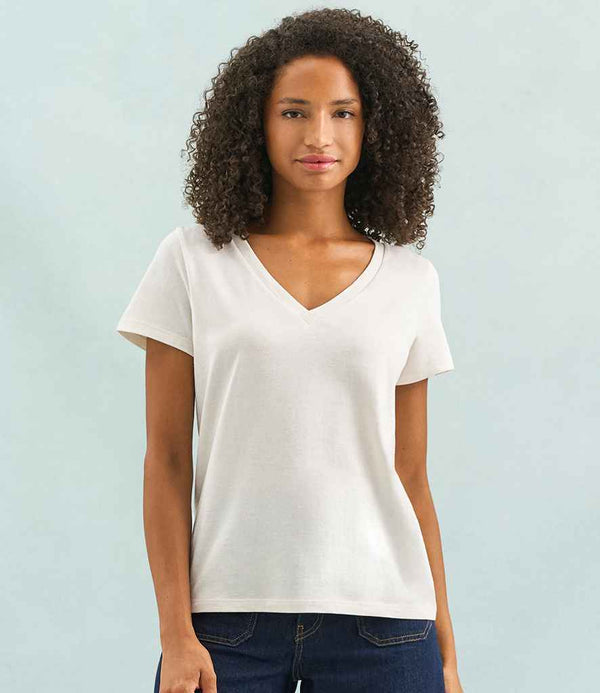 A person with curly hair stands against a light blue background, wearing the SOLS Ladies Regent V Neck T-Shirt by SOLS, featuring a tubular body and modern fit, paired with dark blue jeans.