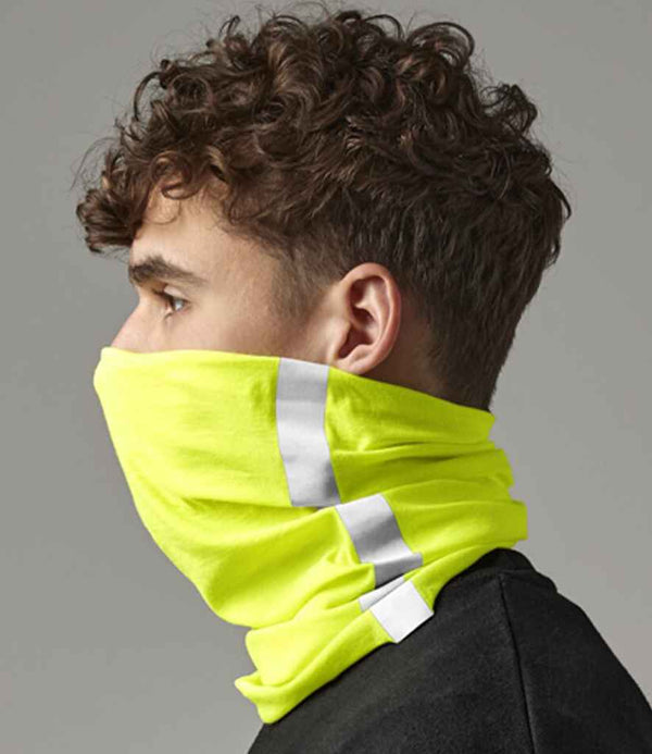 A person with short, curly brown hair wears the Beechfield Morf® Enhanced-Viz by Beechfield—a bright yellow, breathable neck gaiter with two vertical reflective silver stripes—shown in profile against a plain gray background.