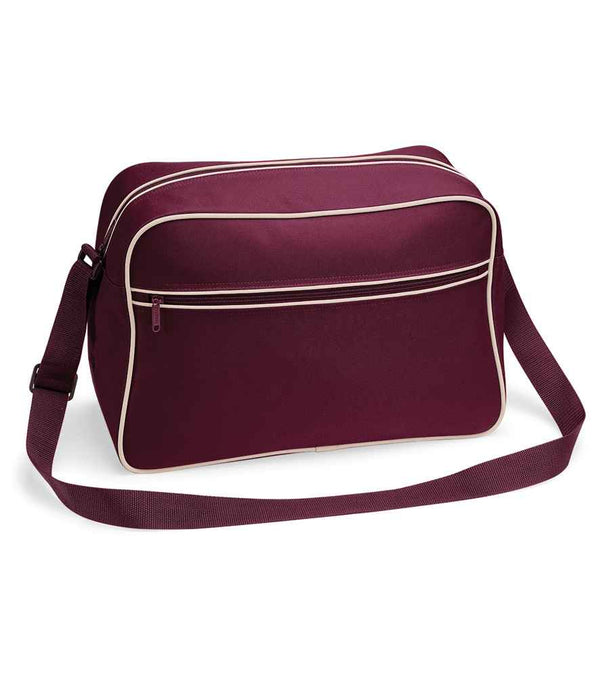 The BagBase Retro Shoulder Bag by BagBase is maroon with white piping, made from recycled polyester, and features a front zipper pocket plus an adjustable strap. It is photographed against a white background.