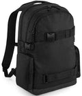 The BagBase Old School Boardpack by BagBase is a black 23L laptop backpack with two main zippered compartments, skateboard carry straps, side pockets, adjustable shoulder straps, and buckle closures, shown on a plain white background.