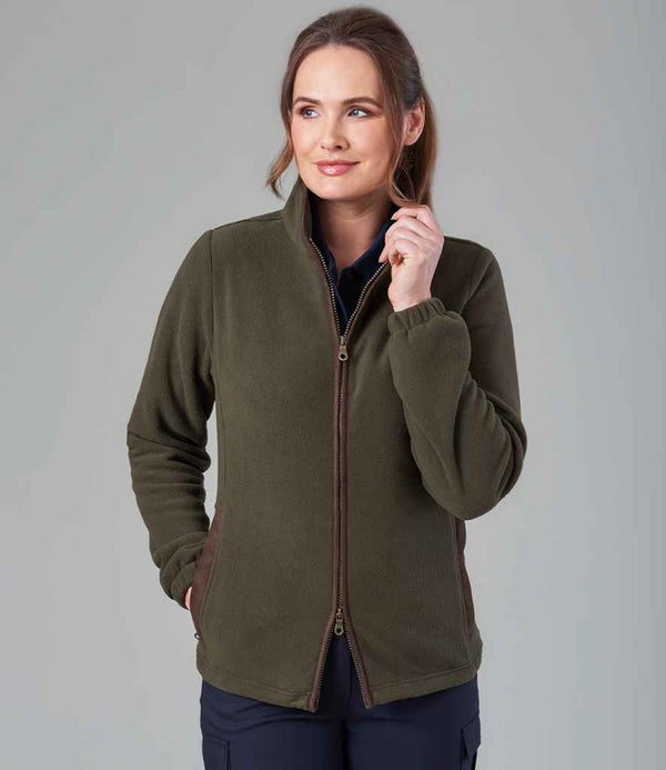 A woman with brown hair wears a Brook Taverner Unisex Baltimore Fleece Jacket in olive green with brown faux suede detail and black pants. She looks to the side, holding the collar against a plain gray background.