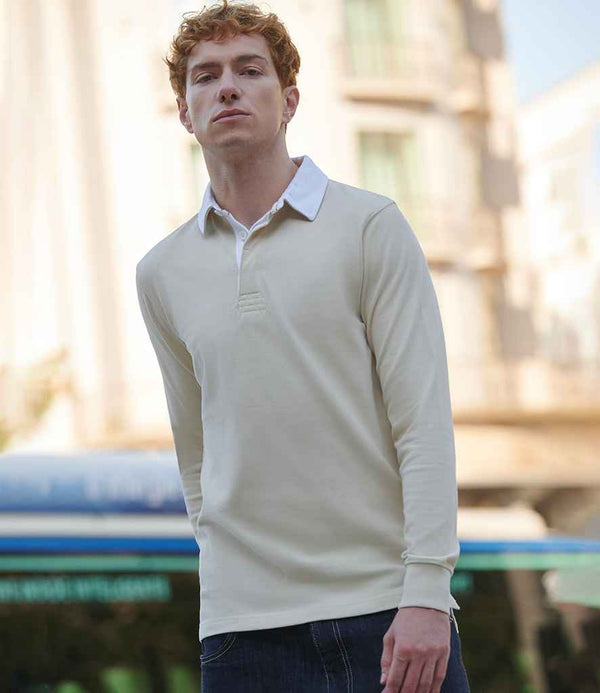 A person with short, curly red hair wears the Front Row Premium Superfit Rugby Shirt by Front Row, featuring a white collar, paired with dark jeans and standing outdoors in an urban setting with blurred buildings in the background.