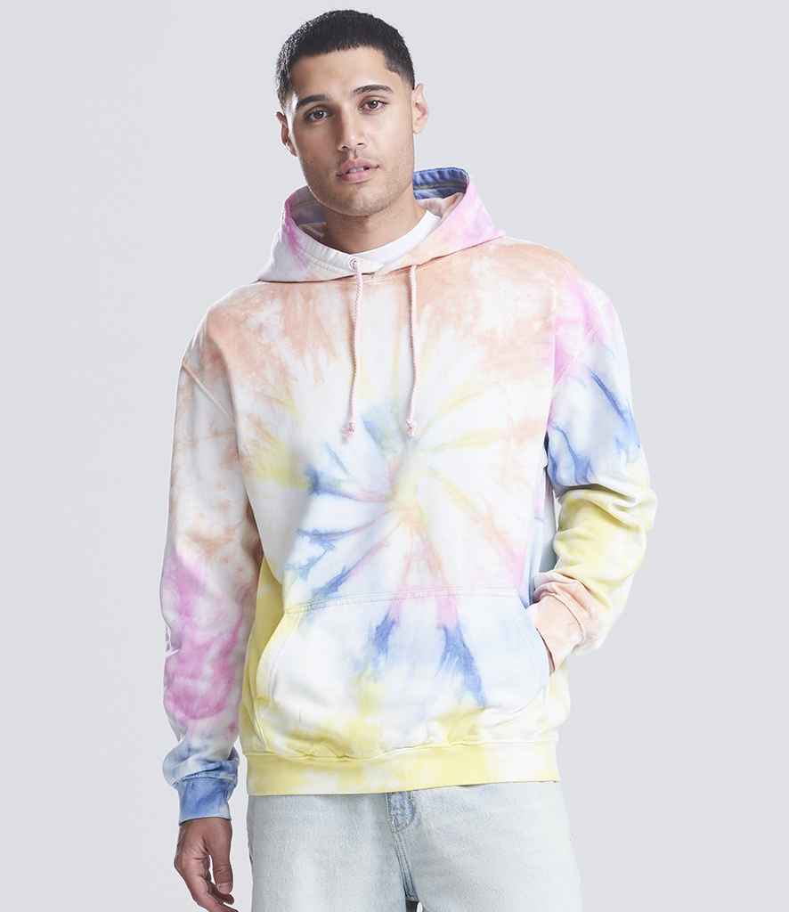 A man faces forward in a pastel AWDis Tie-Dye Hoodie by Just Hoods, featuring yellow, blue, pink, and white brushed back fleece. His right hand is in the front pouch pocket. He pairs the hoodie with light jeans against a light gray background.