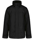 The Kariban Factory Zip Off Sleeve Jacket by Kariban is a black showerproof winter jacket with long sleeves, a high collar, polyester padding, flap-covered front zipper with snap buttons, two side pockets, and weather-resistant material.