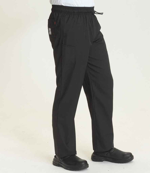 A person wearing Le Chef Professional Trousers by Le Chef, featuring a media pocket, elasticated waistband, and drawstring, paired with black slip-on shoes stands against a plain light background. Only their lower body is visible.