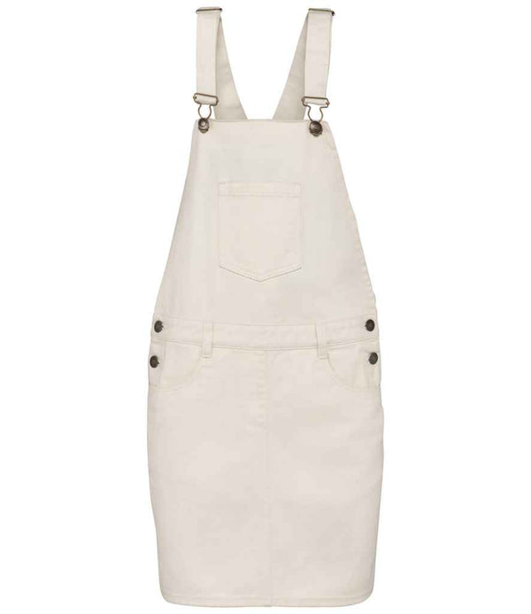 The Native Spirit Ladies Dungarees Dress is a beige denim overall featuring garment-washed fabric, adjustable straps, a chest pocket, recycled side buttons, belt loops at the waist, and two front skirt pockets.