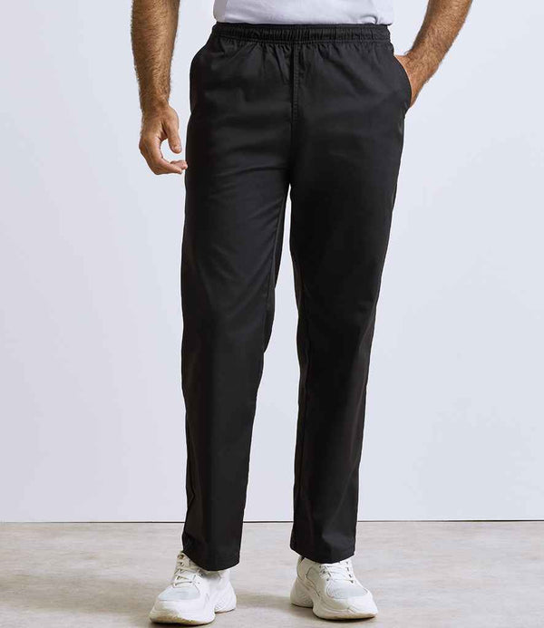 A person wears Premier Essential Chefs Trousers by Premier, featuring an elasticated waistband, with a white shirt and sneakers. Only the lower half of the body is shown against a plain, light background.