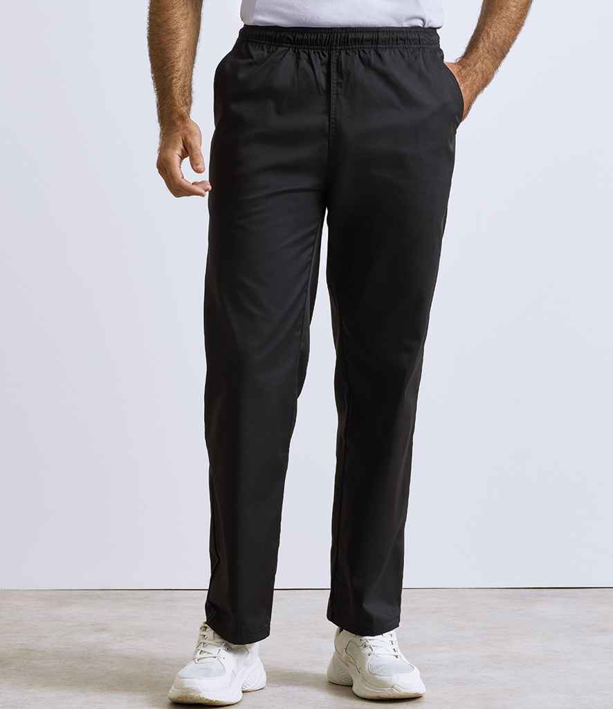A person wears Premier Essential Chefs Trousers by Premier, featuring an elasticated waistband, with a white shirt and sneakers. Only the lower half of the body is shown against a plain, light background.