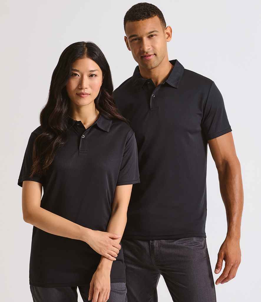 A woman and a man stand side by side against a plain light background, both wearing Premier Coolchecker® Stud Piqué Polo Shirts by Premier with dark pants.