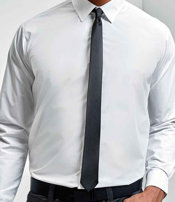 A person wearing a plain white long-sleeve dress shirt, black pants, and the Premier Slim Tie by Premier. The tie’s retro 57-inch slim-line blade is featured. The photo is cropped to show only the upper body, not the face.