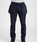 A person wears Portwest WX2™ Eco Stretch Holster Trousers—dark blue with large holster and knee pad pockets—paired with a light shirt and black shoes, shown from the waist down. Brand: Portwest.