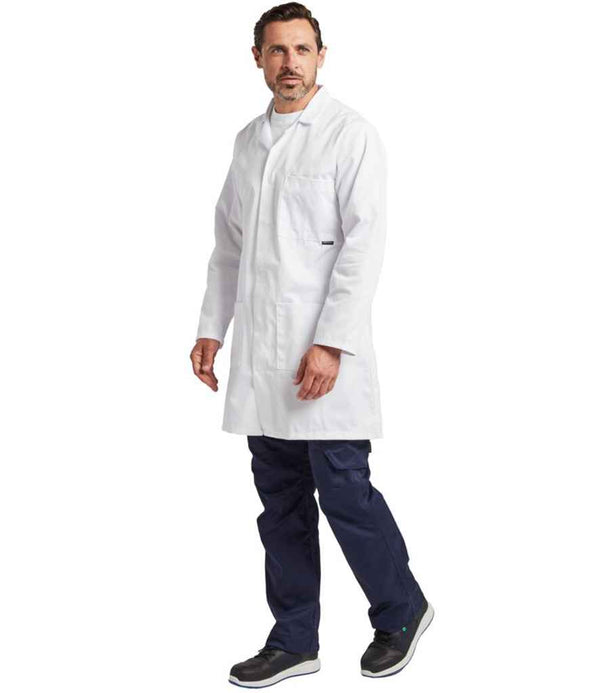 A man with short brown hair and a beard wears a white Portwest Lab Coat over a white shirt and navy pants, paired with black sneakers. He stands against a plain white background, looking slightly to the side.