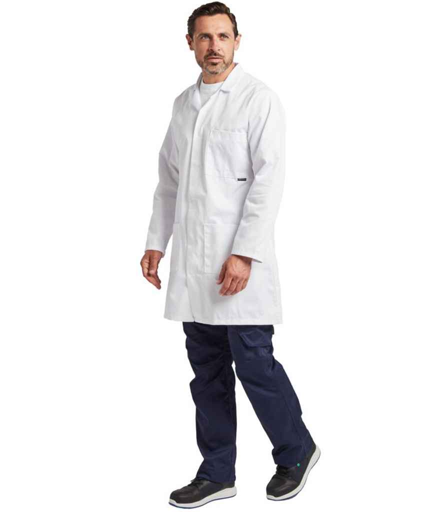 A man with short brown hair and a beard wears a white Portwest Lab Coat over a white shirt and navy pants, paired with black sneakers. He stands against a plain white background, looking slightly to the side.