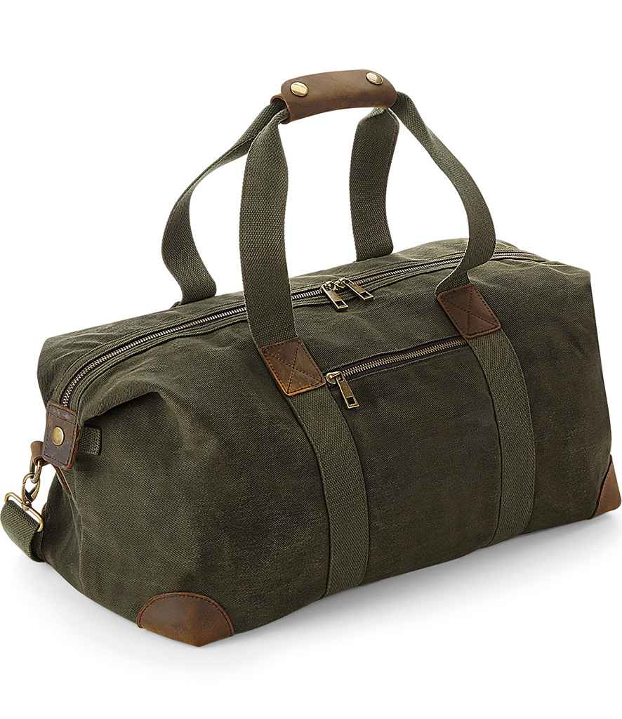 The Quadra Heritage Waxed Canvas Holdall by Quadra features green canvas, brown leather trim, cotton webbing handles with a leather grip, an adjustable shoulder strap, and multiple zippered compartments.