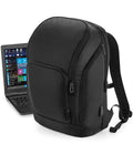 The Quadra Pro-Tech Charge Backpack by Quadra, featuring multiple zippered compartments, an ergonomic back panel, padded straps, and a side USB charging port, stands upright next to an open laptop displaying Windows.