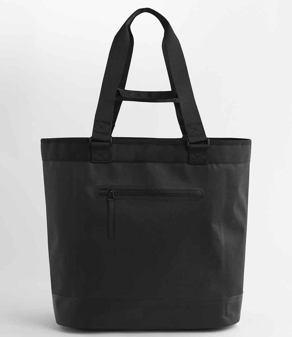 The Quadra Waterproof 35 Litre Tote Bag by Quadra features two long handles, a front zippered pocket, and is shown in black against a plain white background.