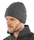 A man with a short beard wears the Result Recycled Thinsulate™ Beanie in dark gray with a deep cuff, paired with a black zip-up jacket. He looks slightly to the side against a plain white background.