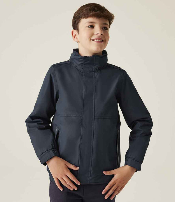 A boy with short brown hair stands against a light background, smiling slightly to the side while wearing the Regatta Kids Dover Waterproof Insulated Jacket by Regatta Professional.