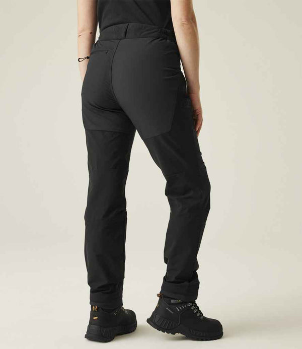 The lower half of a person is shown from behind, wearing Regatta Professional Regatta Ladies Prolite Stretch Trousers and black hiking boots against a plain light background.