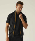 A man stands against a neutral background, wearing the Regatta Professional Regatta Navigate Fleece Bodywarmer over a black short-sleeve shirt. He looks down while holding the unzipped vest near his collar, showing its orange zipper detail.