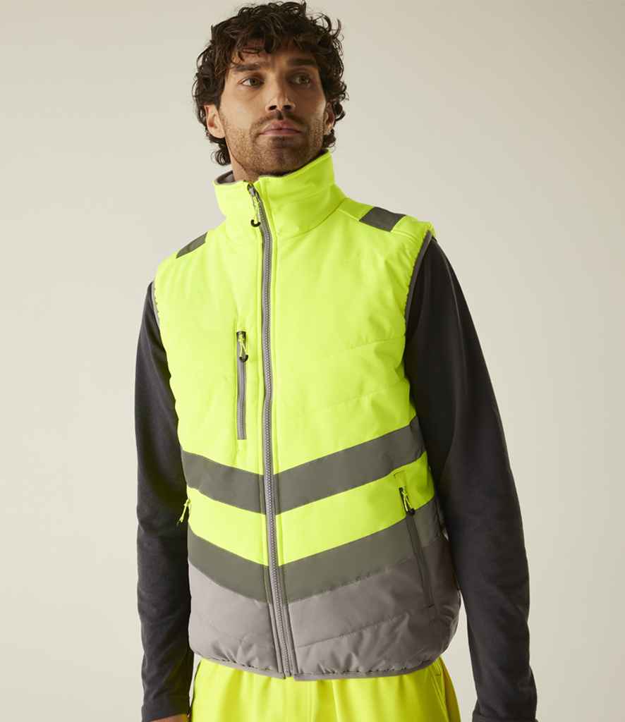 A man wearing a Regatta High Visibility Two Tone Thermal Baffle Bodywarmer, a water repellent, high-visibility yellow vest with gray reflective stripes, stands facing forward against a plain light background.