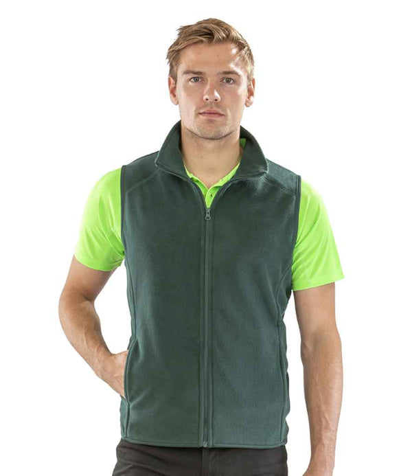 A person faces forward, wearing the Result Core Micro Fleece Gilet in green from Result Core over a bright green short-sleeve polo and black pants, with one hand in the gilet pocket.