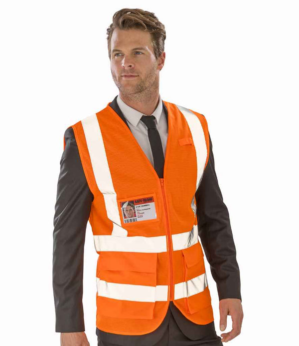 A man in a black suit and tie wears a Result Safe-Guard Executive Cool Mesh Safety Vest with reflective white stripes and an ID badge, standing against a plain white background.
