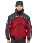 A person wearing a navy blue beanie and the Result Work-Guard Zip Sleeve Heavy Duty Jacket by Result Work-Guard, featuring red and navy colors, multiple pockets, and reflective piping, stands against a plain white background.