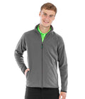 A young man faces forward, smiling, with one hand in his pocket, wearing the Result Recycled Micro Fleece Jacket by Result Recycled over a bright green collared shirt and black pants.
