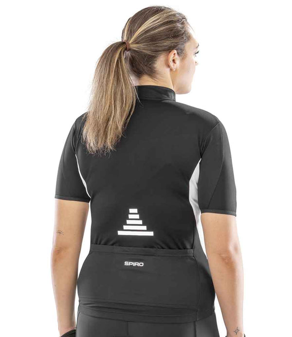 A person with long, light brown hair in a ponytail is seen from the back wearing the Spiro Ladies Bikewear Top, a black and white performance cycling jersey with reflective branding and SPIRO on the lower back.