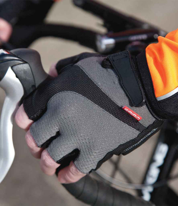 A cyclist grips a handlebar and brake lever while wearing Spiro Fingerless Summer Short Gloves in black and gray, paired with an orange and black long-sleeve top.