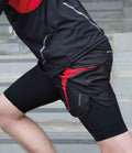 A person in a black and red athletic outfit with Spiro on the shorts stretches one leg forward on concrete steps, wearing the Spiro Compression Quad Sleeve to help manage sweat and reduce muscle fatigue. Their face is not visible.