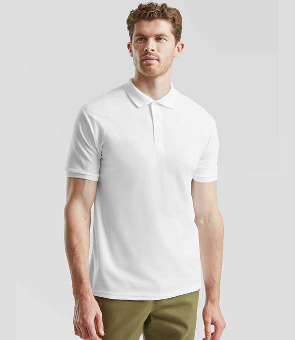 A man stands against a plain gray background, facing forward in a neutral pose, wearing a Fruit of the Loom Heavy Poly/Cotton Piqué Polo Shirt in white and olive green pants.