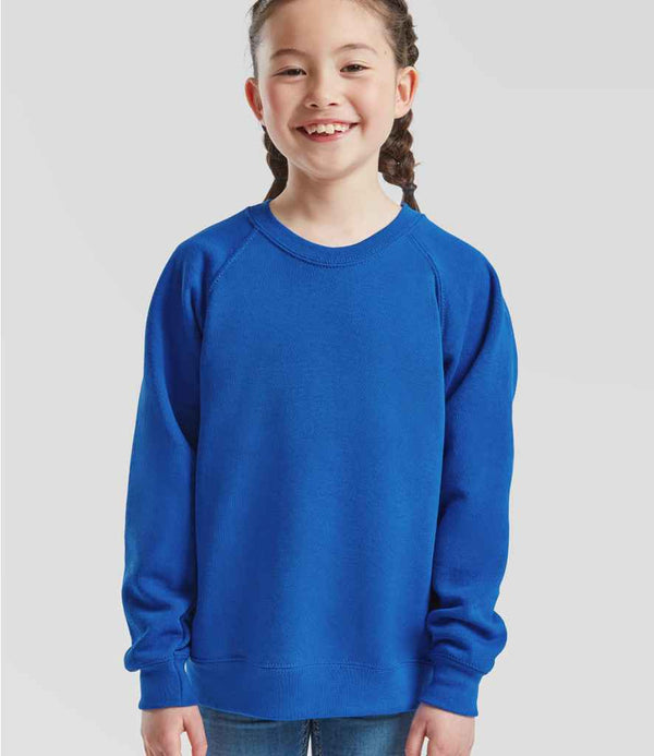A young girl with braided hair smiles, wearing the Fruit of the Loom Kids Classic Raglan Sweatshirt in bright blue and blue jeans, standing against a plain light gray background.