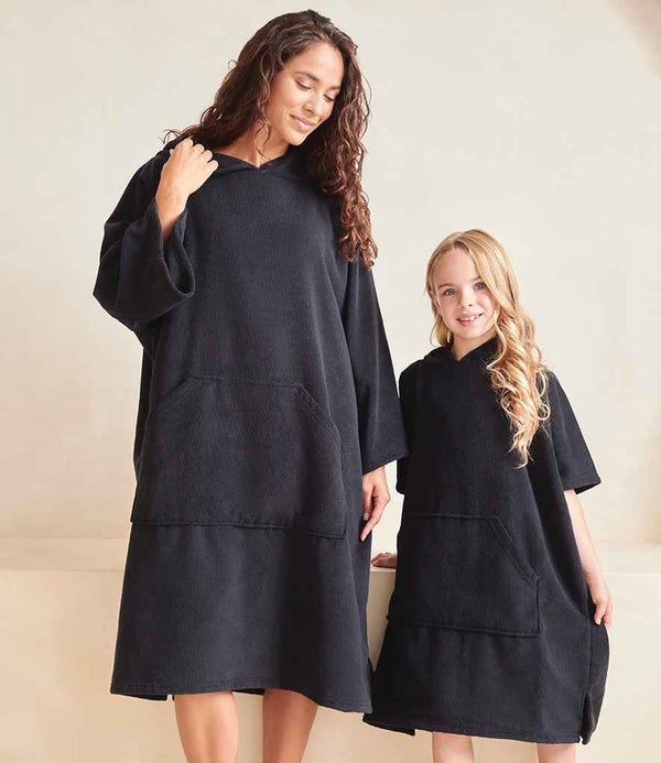 An adult and a child stand side by side wearing oversized black Towel City Adult Ponchos with long sleeves and large front pockets, posing against a plain, light-colored background.
