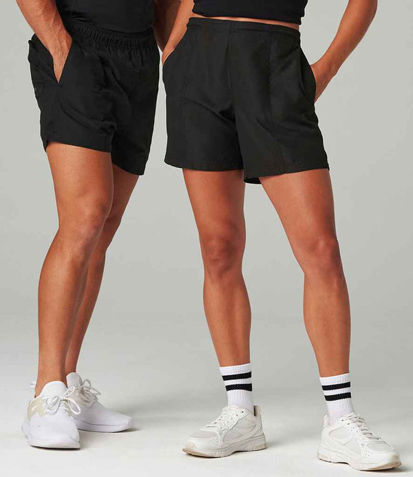 Two people stand side by side, both wearing Tombo All Purpose Mesh Lined Shorts by Tombo and white sneakers. One has hands in pockets and wears white socks with black stripes. Both are photographed from the waist down.