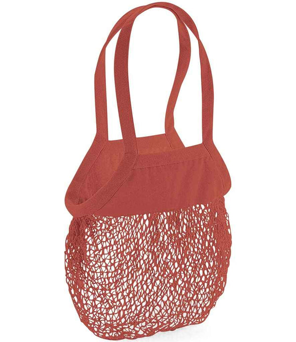 The Westford Mill Organic Cotton Mesh Grocery Bag by Westford Mill is a red bag with a solid cotton top, sturdy shoulder straps, a mesh bottom half, and a 10L capacity. Shown empty against a white background.