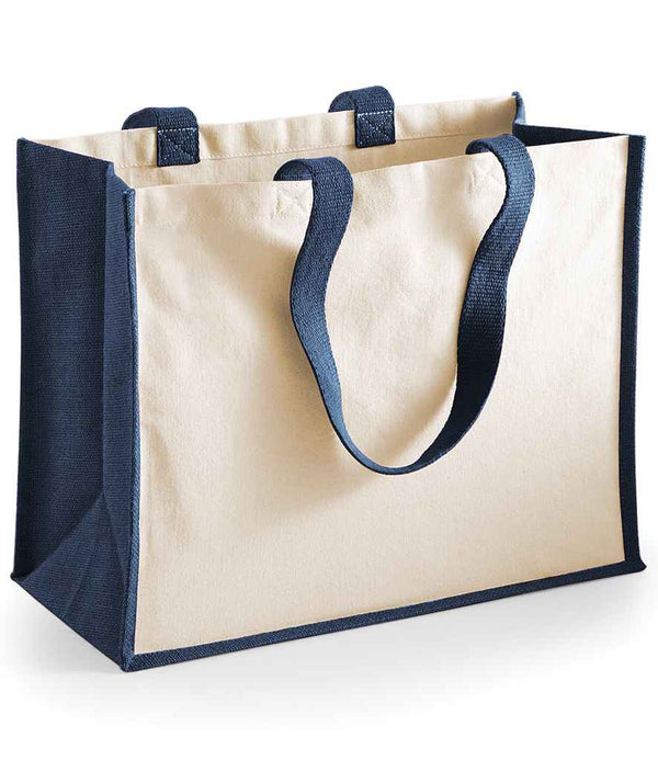 The Westford Mill Printers Jute Classic Shopper by Westford Mill is a beige canvas tote with dark blue handles and trim, sturdy side panels, an open top, reinforced corners, and practical storage for everyday essentials.