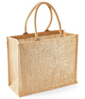 The Westford Mill Shimmer Jute Shopper is a tan rectangular tote bag with gold shimmer thread, sturdy cotton handles, a glittery white front, flat bottom, and a practical 21L capacity—stylish and durable from Westford Mill.