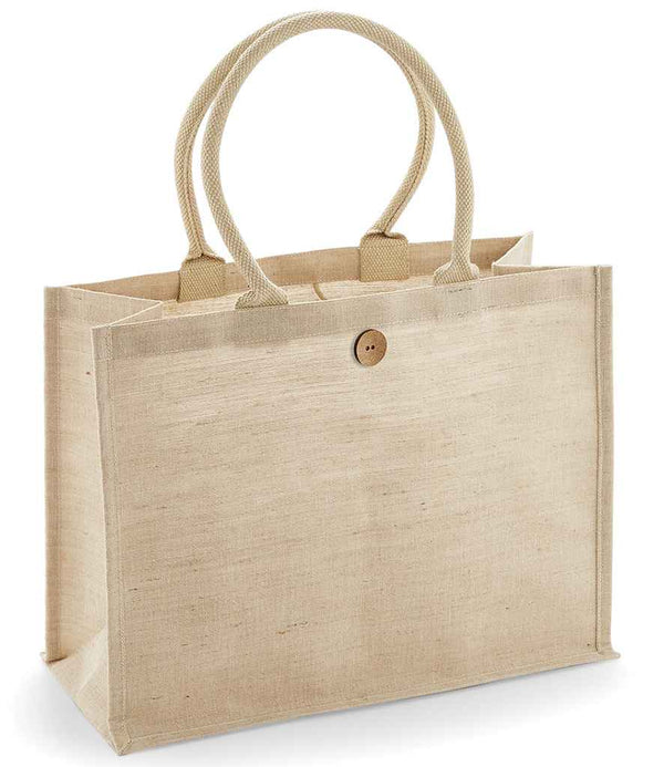 The Westford Mill Juco Shopper by Westford Mill is a beige, rectangular jute-cotton blend tote with sturdy cotton handles, a brown button closure, flat base, reinforced edges, and a roomy 21-litre capacity.